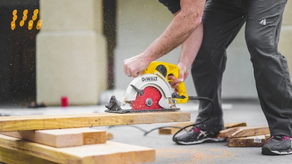 Photo by Greyson Joralemon man in black sweatpants using DEWALT circular saw and cutting a wood plank