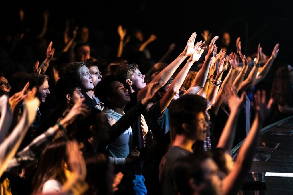 Photo by NATHAN MULLET people raising their hands during night time